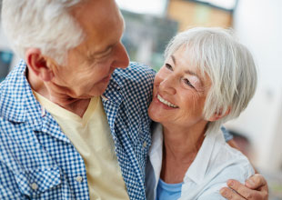 Image of an older couple smiling and embracing one another.